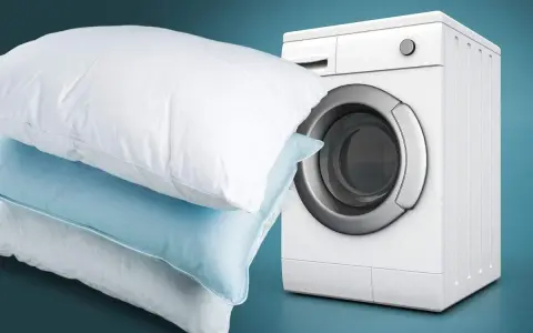 Impara come lavare i cuscini in lavatrice per un sonno fresco e igienico. Cuscini bianchi e azzurri accanto a una lavatrice bianca.