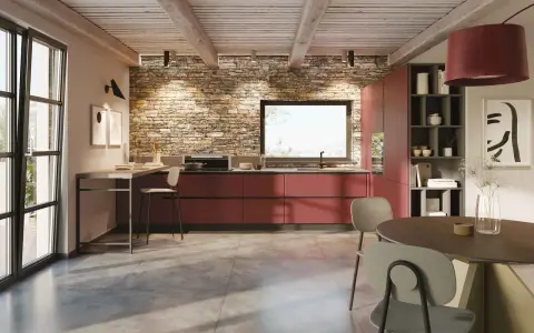 Cucina moderna con mobili rossi a vista, parete in pietra e un'isola che offre idee cucine ad angolo. Tavolo rotondo e sedie completano l'ambiente.