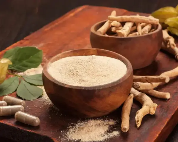 Radici, polvere e capsule di ashwagandha su tagliere di legno. Scopri come assumere ashwagandha per il benessere.