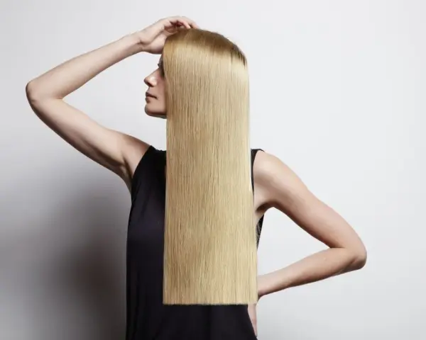 Donna con lunghi capelli biondi lisci, che mostra come lisciare i capelli a casa per un look impeccabile.