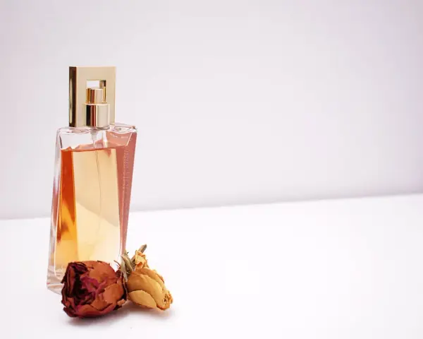 Elegante flacone di profumo dorato con rose secche, un'ispirazione su come scegliere un profumo che ti rappresenti.