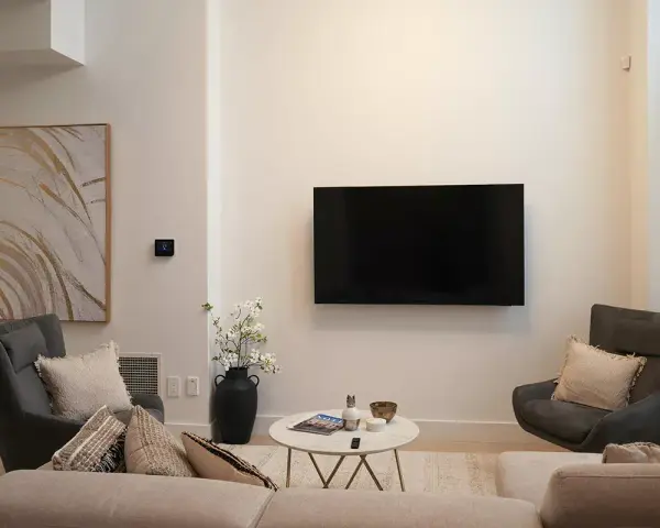 Soggiorno con TV a parete, divano, poltrone e tavolino. L'arredamento minimalista crea un'atmosfera rilassante.