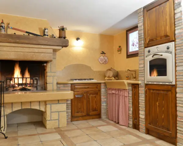 Accoglienti cucine di campagna con camino acceso, mobili in legno scuro e dettagli rustici. Un angolo cottura funzionale e un'atmosfera calda e invitante.