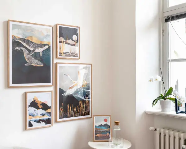 Un modo originale per appendere quadri: balene, paesaggi desertici, montagne e gru in volo decorano una parete chiara, creando un'atmosfera artistica.