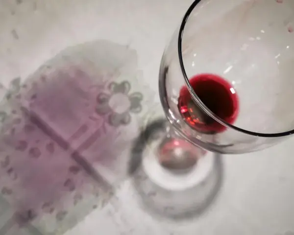 Un bicchiere di vino rosso rovesciato ha lasciato delle macchie sul tovagliolo, creando un'atmosfera di festa finita.