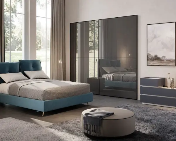 Un letto blu moderno, un armadio a specchio e quadri paesaggistici creano camere da letto da sogno.