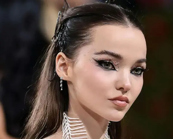 Occhi da sirena scintillanti con strass e eyeliner drammatico, capelli raccolti con accessori metallici.