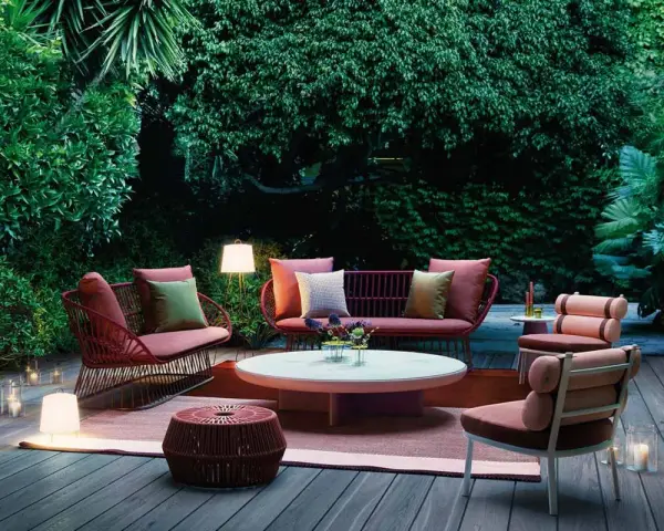 Un terrazzo accogliente con mobili da esterno color corallo e illuminazione soffusa, ideale per godersi la sera.