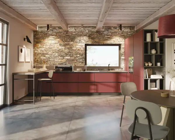 Cucina moderna con mobili rossi a vista, parete in pietra e un'isola che offre idee cucine ad angolo. Tavolo rotondo e sedie completano l'ambiente.