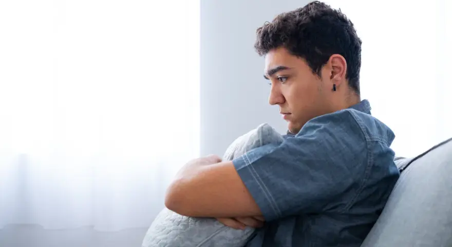 Ragazzo pensieroso abbraccia un cuscino, riflettendo sull'insonnia adolescenza rimedi naturali.