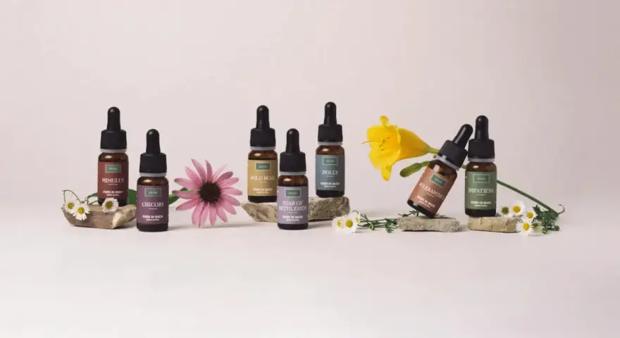 Flaconi di Fiori di Bach Rescue Remedy con Mimulus, Chicory, Wild Rose, Star of Bethlehem, Holly, Scleranthus e Impatiens, circondati da fiori.