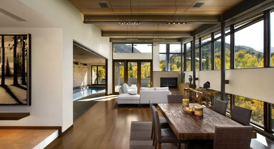 Ampio soggiorno con piscina interna, camino, tavolo da pranzo in legno e vista panoramica. Un perfetto test stile arredamento moderno.