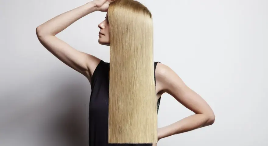 Donna con lunghi capelli biondi lisci, che mostra come lisciare i capelli a casa per un look impeccabile.