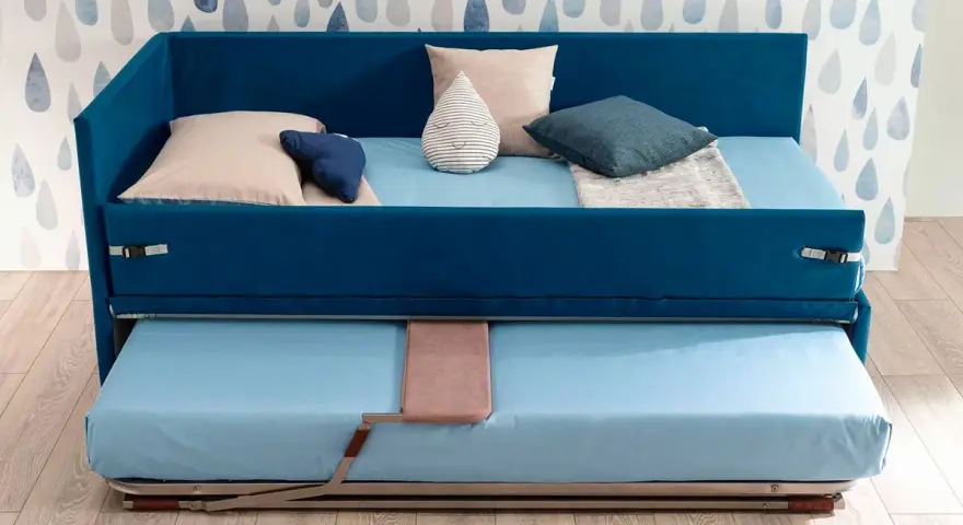Camera studio con divano letto blu, con un secondo letto estraibile sotto. Perfetto per ospitare amici o per un riposino.