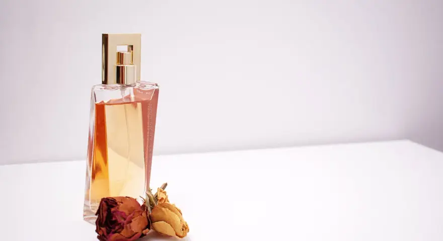 Elegante flacone di profumo dorato con rose secche, un'ispirazione su come scegliere un profumo che ti rappresenti.