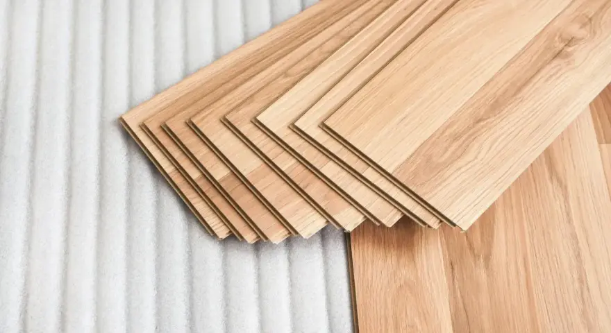 Assortimento di listoni di legno betulla colore chiaro, pronti per essere posati su un tappeto protettivo bianco.