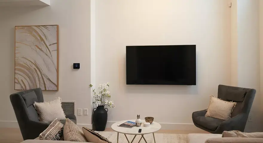 Soggiorno con TV a parete, divano, poltrone e tavolino. L'arredamento minimalista crea un'atmosfera rilassante.