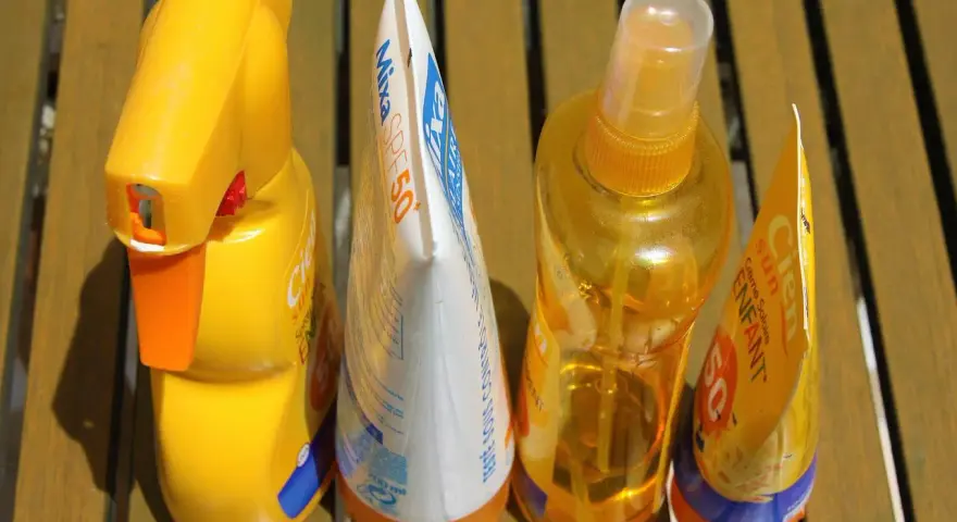 Prodotti solari scaduti, tra cui una crema Mixa SPF50 e spray Cien, pronti per essere smaltiti. Dove si buttano le creme corpo scadute?