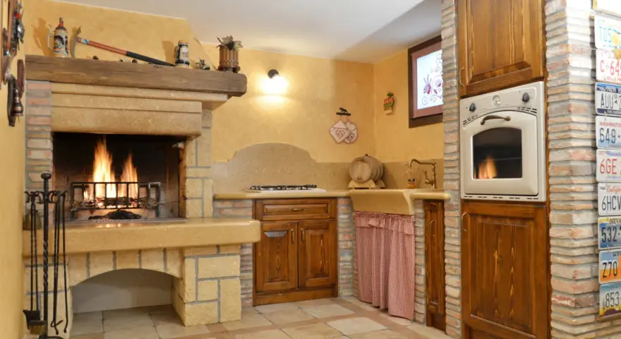 Accoglienti cucine di campagna con camino acceso, mobili in legno scuro e dettagli rustici. Un angolo cottura funzionale e un'atmosfera calda e invitante.