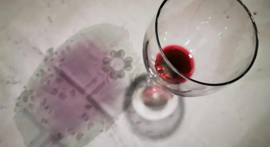 Un bicchiere di vino rosso rovesciato ha lasciato delle macchie sul tovagliolo, creando un'atmosfera di festa finita.
