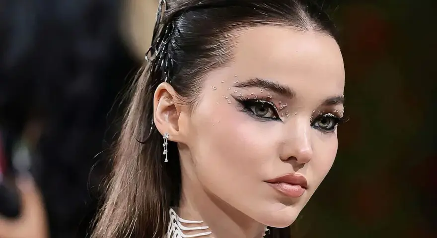 Occhi da sirena scintillanti con strass e eyeliner drammatico, capelli raccolti con accessori metallici.