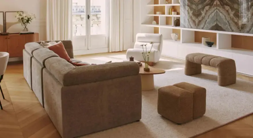 Soggiorno con divano componibile, poltrona, pouf e panca. Arredamento casa stile moderno con mobili in legno e tessuti neutri.