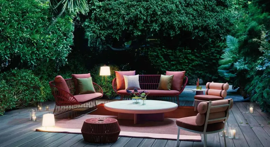 Un terrazzo accogliente con mobili da esterno color corallo e illuminazione soffusa, ideale per godersi la sera.