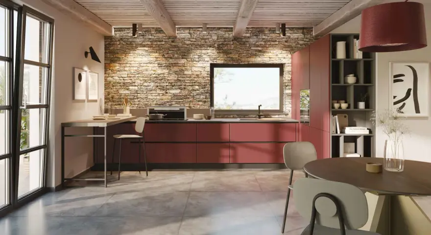 Cucina moderna con mobili rossi a vista, parete in pietra e un'isola che offre idee cucine ad angolo. Tavolo rotondo e sedie completano l'ambiente.
