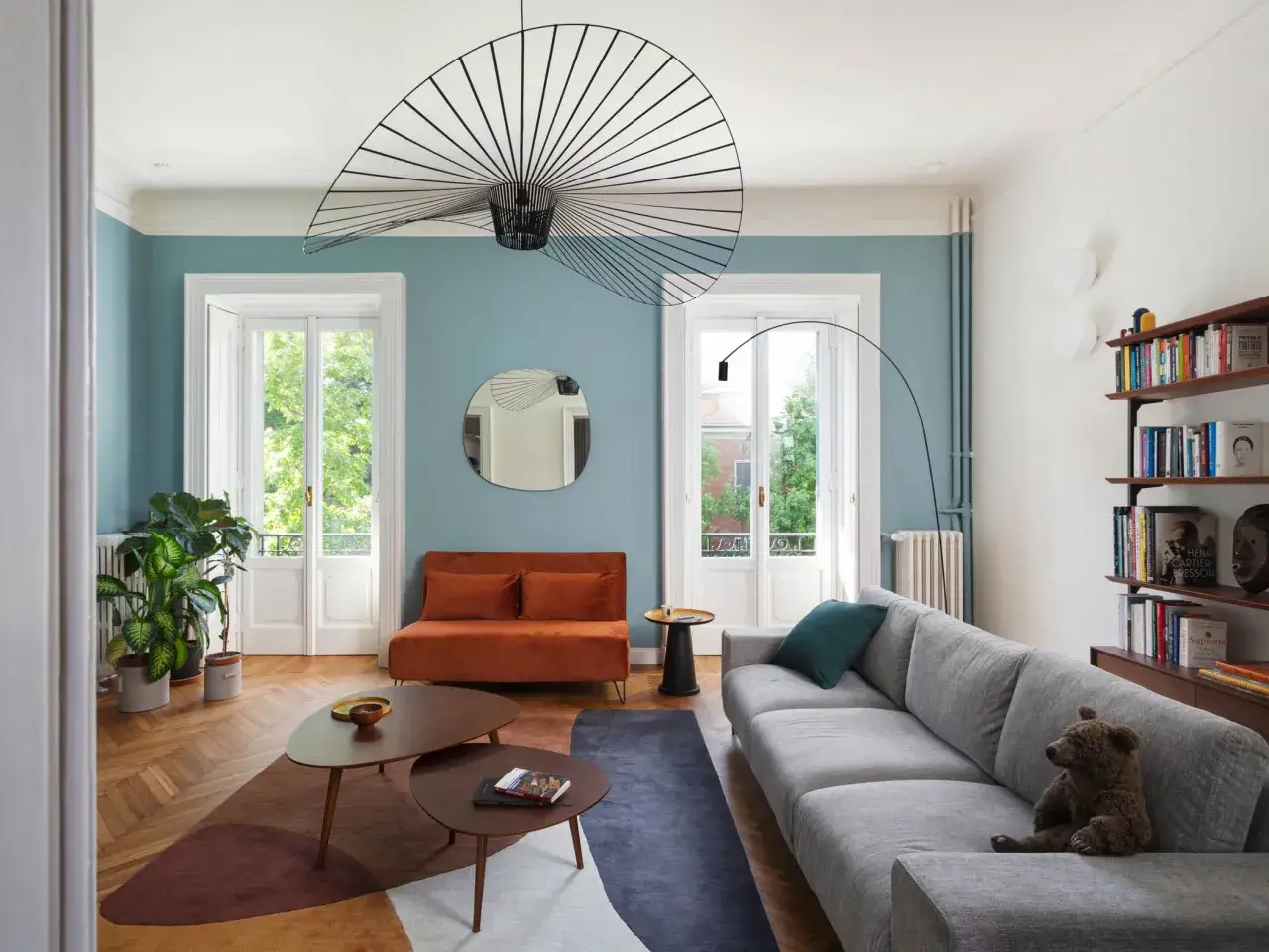 Soggiorno moderno con pareti color tortora e arredi accoglienti. Un divano grigio, un divanetto arancione e tavolini di design creano un ambiente invitante, perfetto per chi cerca idee pareti colorate particolari.