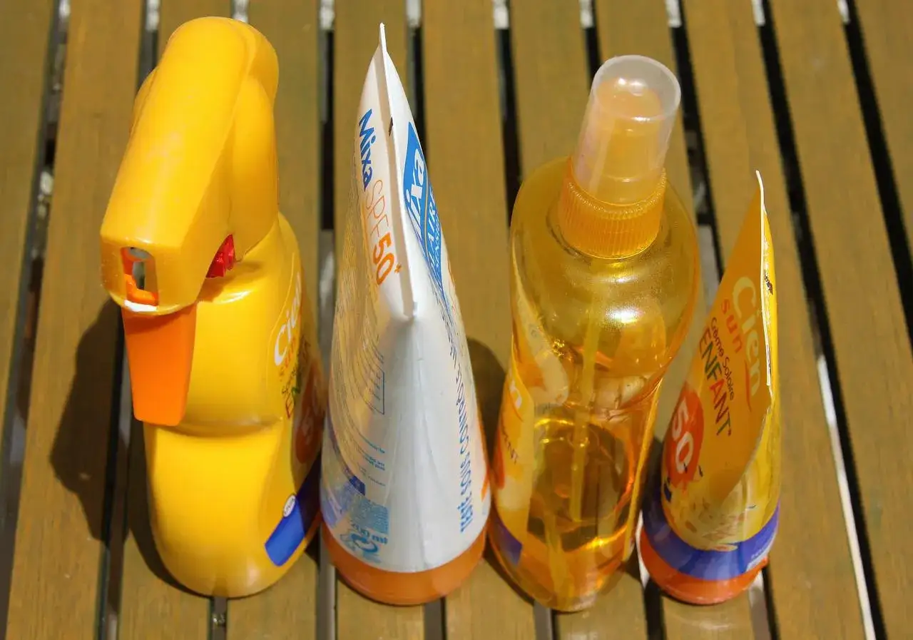 Prodotti solari scaduti, tra cui una crema Mixa SPF50 e spray Cien, pronti per essere smaltiti. Dove si buttano le creme corpo scadute?
