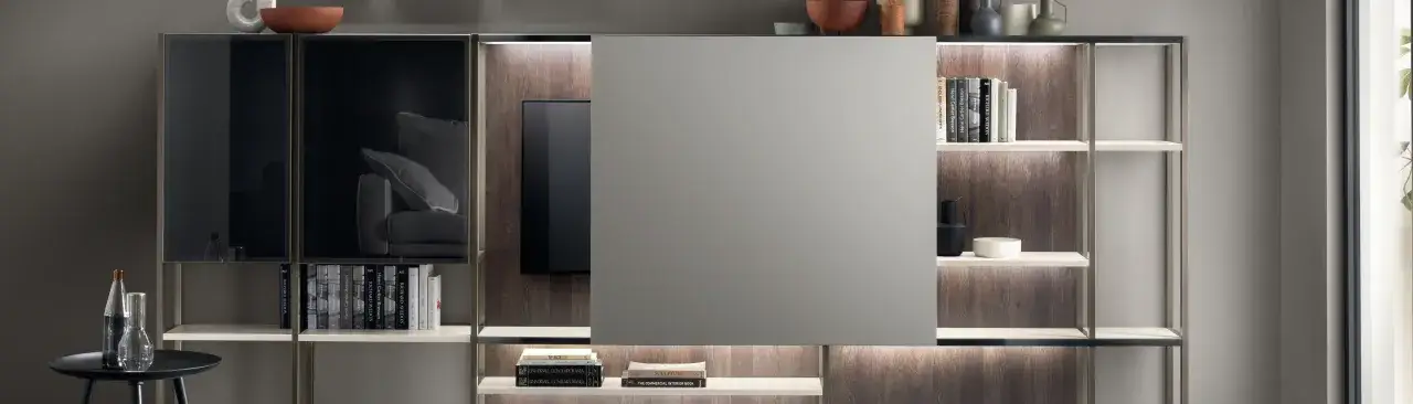 Mobile moderno con ante scorrevoli che nascondono la TV, libreria integrata con illuminazione e oggetti decorativi.