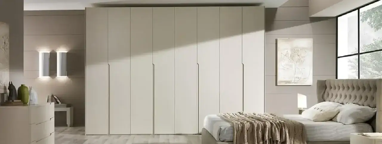 Ampia stanza da letto con imponenti armadi chiusi, un letto accogliente e un quadro astratto.
