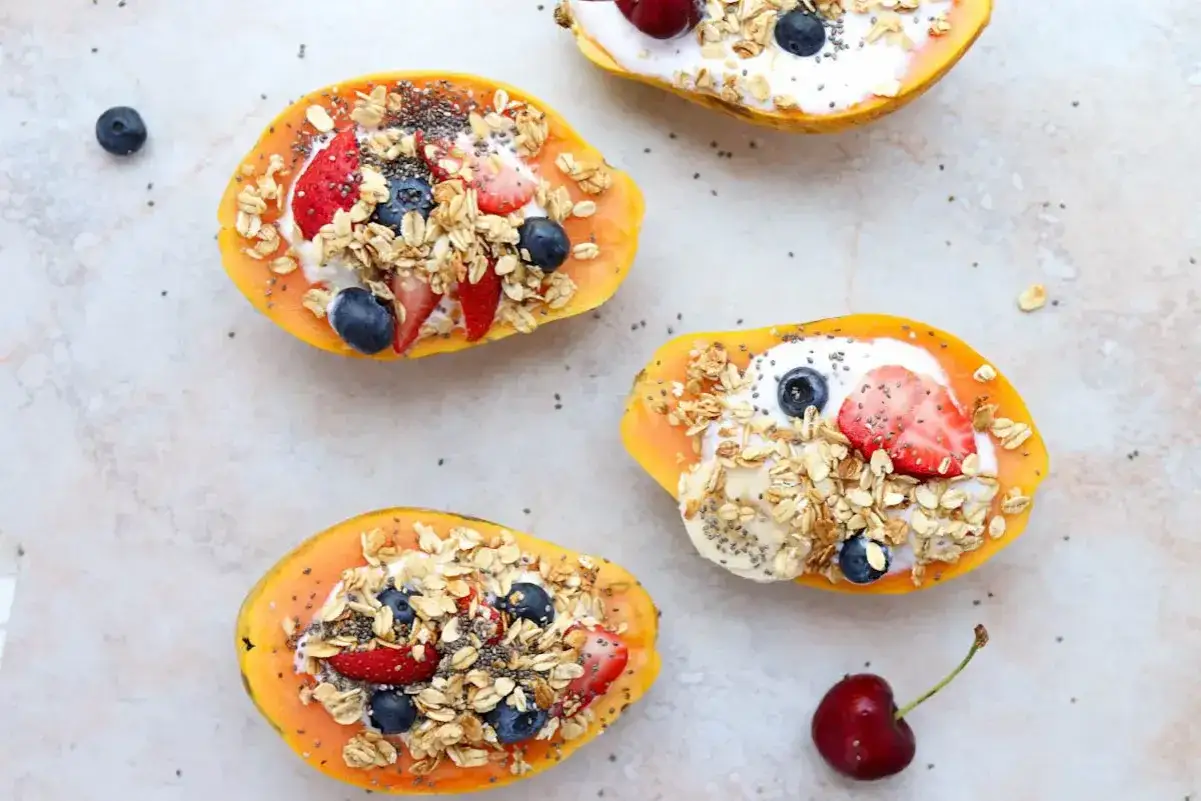 Coppette di papaya ripiene di yogurt, frutta fresca e granola. Un pasto sano per un intestino felice.