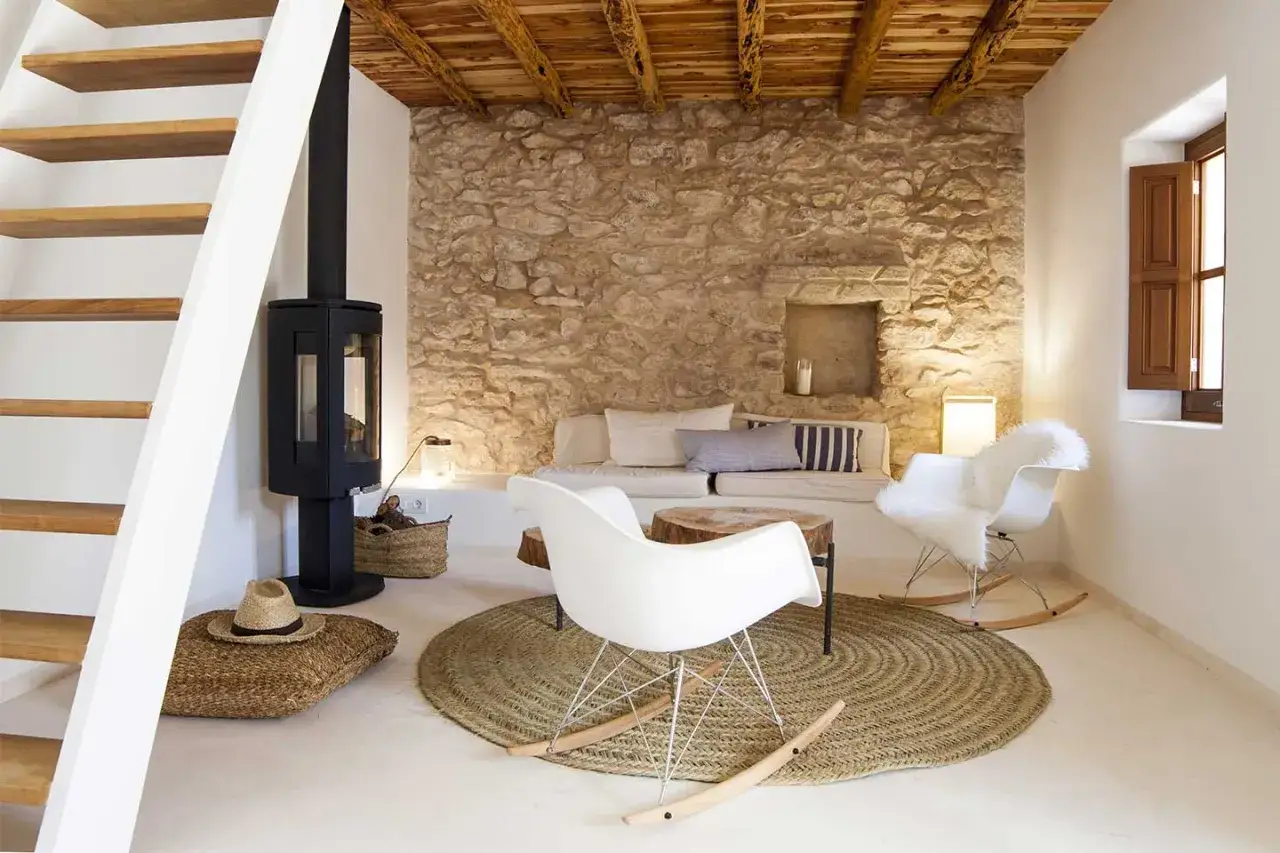 Un soggiorno con camino, divano in pietra e sedie moderne crea un'atmosfera stile cozy.