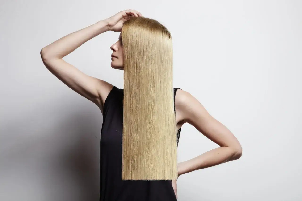 Donna con lunghi capelli biondi lisci, che mostra come lisciare i capelli a casa con facilit&agrave;.
