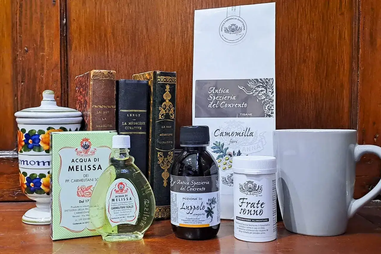 Rimedi naturali per l'insonnia adolescenza: acqua di melissa, luppolo, camomilla e integratori per il sonno, accanto a libri antichi.