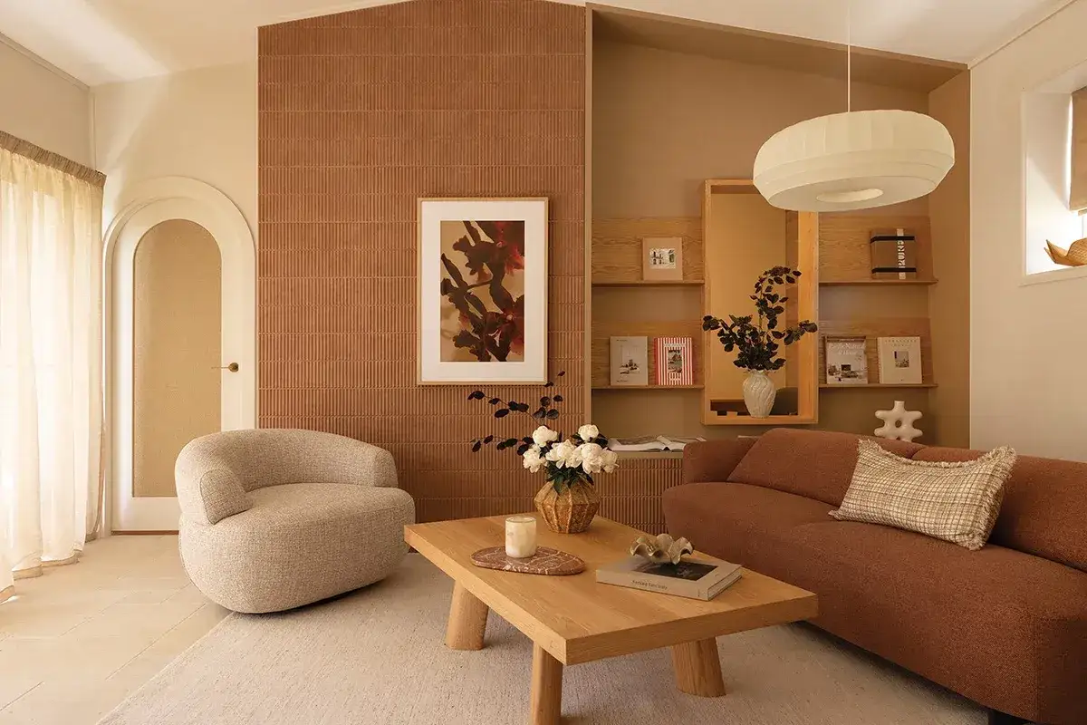 Un salotto accogliente con divano color terra, poltrona bombata e tavolino in legno. Un perfetto test stile arredamento con texture naturali e toni caldi.