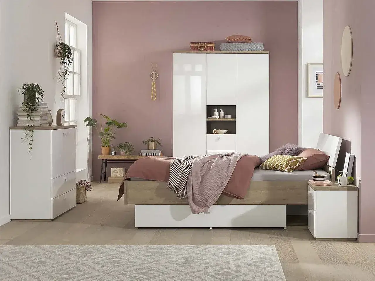 Camera da letto moderna con letto una piazza e mezza, armadio bianco e comodino. Pareti rosa cipria e pavimento in legno.
