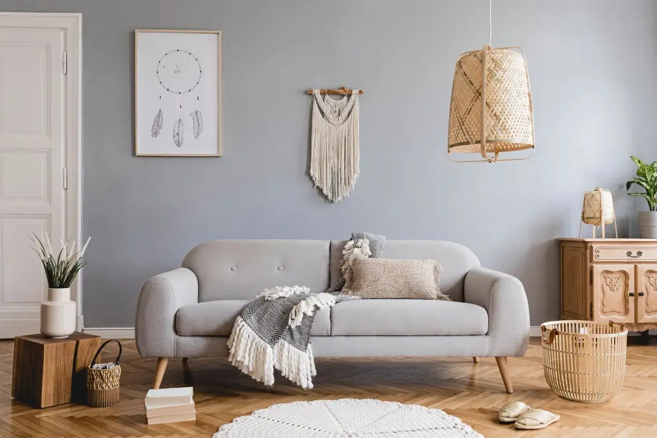 Soggiorno in stile nordico, con divano grigio, coperte, cuscini e decorazioni in macram&egrave;. Un'atmosfera accogliente in stile scandinavo.