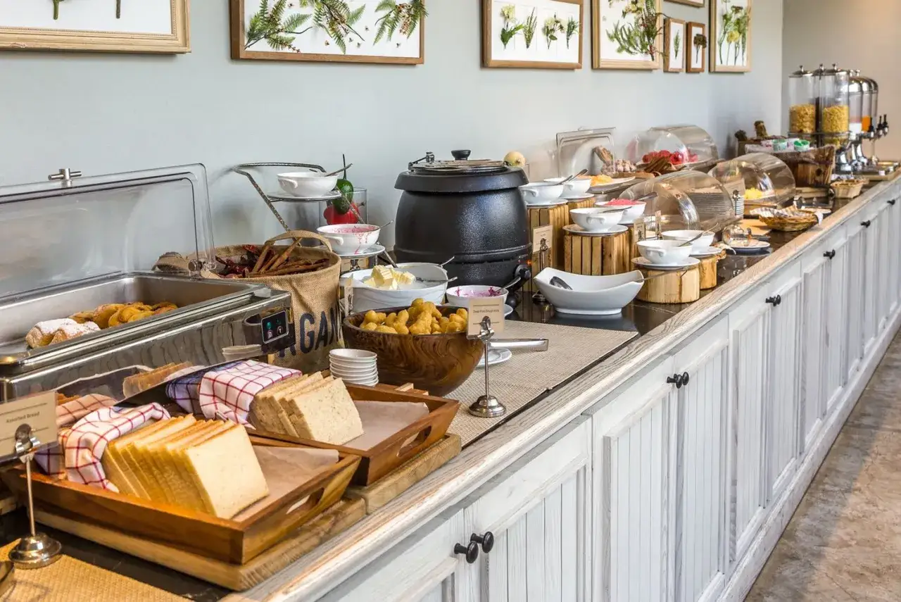 Buffet per la colazione in un B&B: pane affettato, dolci, cereali, frutta e bevande.
