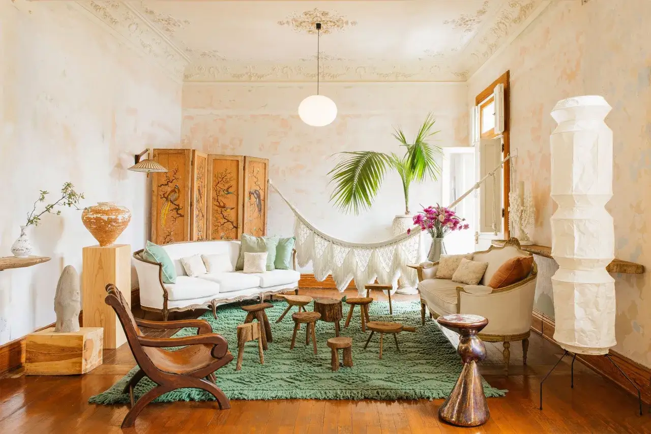 Salotto con divani bianchi, amaca in macram&egrave;, tappeto verde e arredi in legno. Un'atmosfera rilassata e accogliente, perfetta per uno stile boho chic casa.