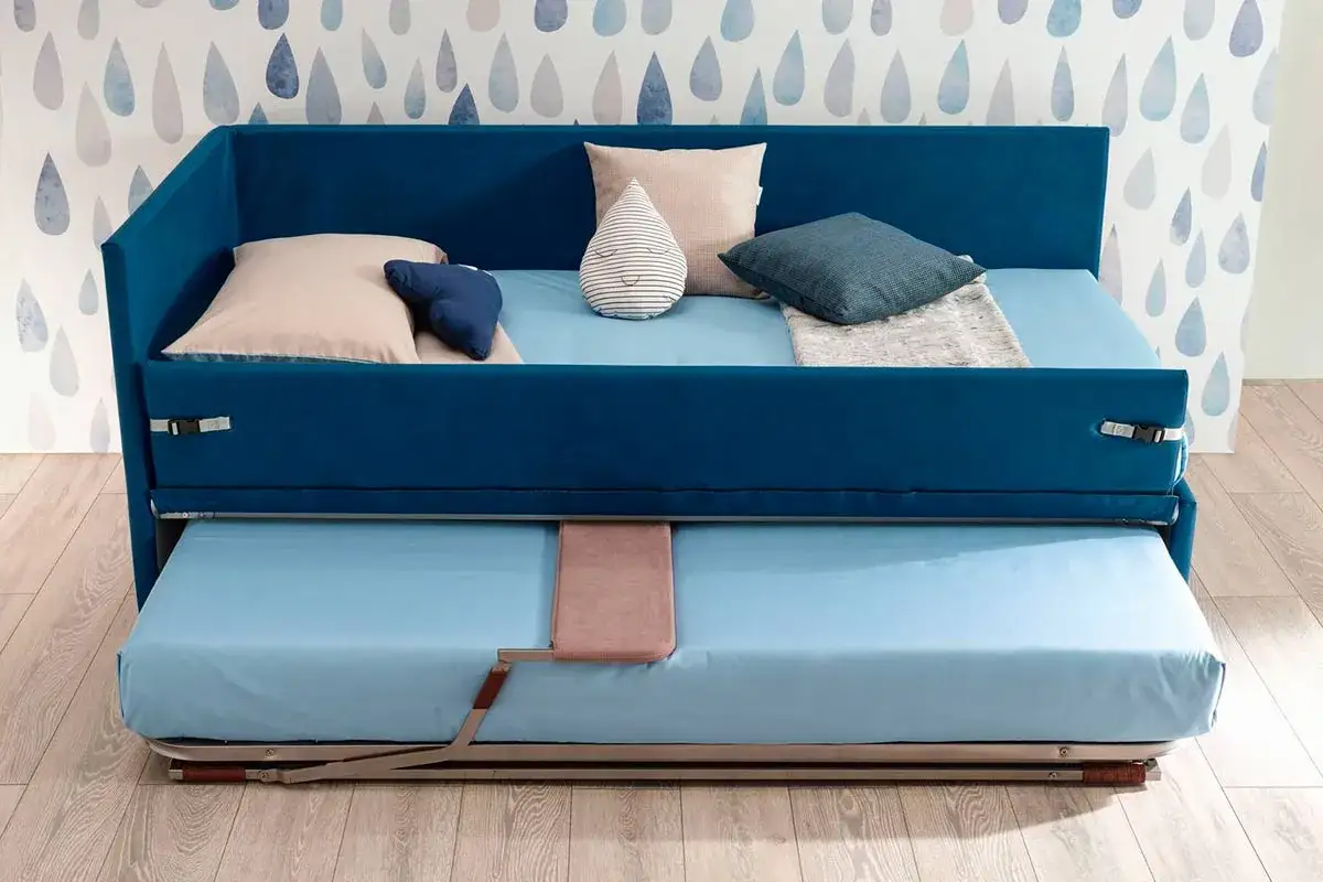 Camera studio con divano letto blu, con un secondo letto estraibile sotto. Perfetto per ospitare amici o per un pisolino.