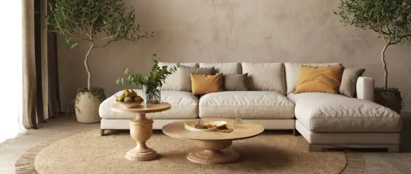 Soggiorno beige e bianco con divano modulare, tavolini in legno, piante e tappeto in juta.