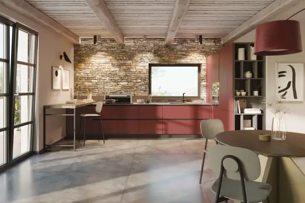 Cucina moderna con mobili rossi a vista, parete in pietra e un'isola che offre idee cucine ad angolo. Tavolo rotondo e sedie completano l'ambiente.