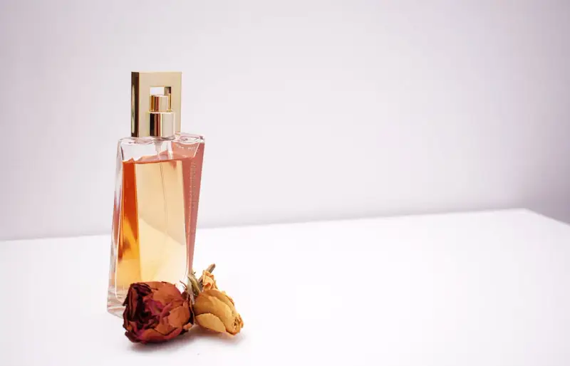Elegante flacone di profumo dorato con rose secche, un'ispirazione su come scegliere un profumo che ti rappresenti.